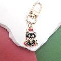 Detailaufnahme von Weihnachtskatze-Schlüsselanhänger aus Emaille mit Schal und Kerze - Schwarze Katze mit Kerze