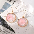 Dettaglio di petali di fiori di ciliegio rosa in orecchini di resina a forma di cuore - Tondo di Pizzo