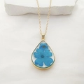 Macro view of teardrop necklace with real blue dried flowers in gold-plated frame - Necklace / Blue