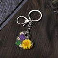 Detail shot of acrylic heart keychain featuring a yellow daisy and real purple dried flowers - Yellow Daisy and Purple Flowers (K17)