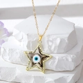 Détail du pendentif étoile dorée avec motif œil bleu posé sur une pierre blanche - Noir