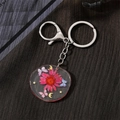 Detail of round resin keychain featuring real pink dried flowers and butterfly charms - Colorful Butterfly Rose Flower (Silver Clasp)