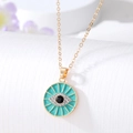 Macro shot of evil eye pendant with green enamel and sparkling crystals on golden chain - Round Lake Blue Eye