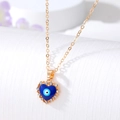 Macro shot of gold heart necklace with blue evil eye enamel and crystal detail - Gold Enamel Heart