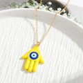 Detail of a golden Hamsa Hand necklace with yellow enamel and blue evil eye charm - Yellow Hand