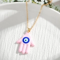 Detailed macro view of the pink Hamsa Hand pendant with Evil Eye on a golden chain - Pink Hamsa Hand