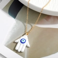 Detail of Hamsa Hand necklace with white enamel and blue Evil Eye charm on gold chain - White Mickey Glove Style