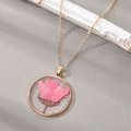 Detailed close-up of a pink dried flower resin pendant with gold flakes on grey fabric - September Pink Chrysanthemum (Necklace)
