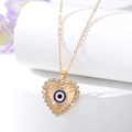 Golden heart Evil Eye pendant necklace with blue crystals on white marble stand - Gold Rhinestone Heart Eye