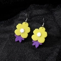 Détail de boucles d'oreilles fleurs en acrylique jaune et feuilles mauves sur tissu noir - Fleur Jaune (Crochet en Argent)