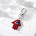 Makro-Detail von rotem Hamsa-Hand Schlüsselanhänger mit blauem bösem Blick Anhänger - Burgunderrot