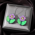 Detailed macro view of purple acrylic flower earrings with green leaves on satin - Purple Flower Green Leaf