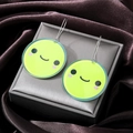 Süße grüne Acryl-Ohrringe mit Smiley-Gesicht und silbernen Haken auf Schmuckschatulle - Smiley