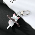 Nahaufnahme von niedlichem weißen Katzen-Schlüsselanhänger mit silbernem Karabiner - Katze Auf Zweig