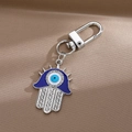 Hamsa Hand Schlüsselanhänger mit blauem Evil Eye und funkelnden Kristallen auf Satin - Stachelige Hand der Fatima / Silber