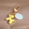 Detail of matte yellow balloon dog keychain with golden alloy edges and oval tag - Yellow Balloon Dog