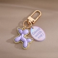 Détail du porte-clés chien ballon violet avec bords dorés et breloque sur tissu - Chien Ballon Violet