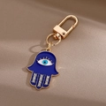 Détail du porte-clés main de Hamsa avec œil bleu et strass blancs étincelants - Main Bleu Foncé / Or