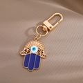 Dettaglio portachiavi Mano di Fatima e Malocchio con smalto blu e placcatura - Portachiavi Mano di Fatima Traforata Oro