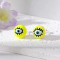 Macro shot of neon yellow evil eye stud earrings with blue pupils on white stone base - Yellow Eye