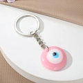 Rosa Evil Eye Schlüsselanhänger aus Harz mit poliertem Silberring auf seidigem Hintergrund - Rosa