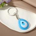 Detail of blue teardrop evil eye keychain on white plate with purple flowers - Water Drop Sky Blue