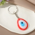 Detailopname van een druppelvormige Turkse Evil Eye sleutelhanger op een wit bord - Rode Waterdruppel