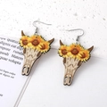 Details von Western-Ohrringen mit Kuhschädel und Sonnenblume auf Steinhintergrund - Floraler Stierschädel-Stil