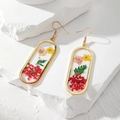 Dettaglio di orecchini ovali dorati con fiori secchi colorati in resina trasparente - Fiore Secco Ovale Lungo