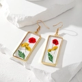 Dettaglio macro di orecchini rettangolari in oro con fiori secchi in resina trasparente - Fiore Secco Rettangolo