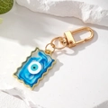 Dettaglio del portachiavi malocchio con bordi dorati ondulati e trama in marmo blu - Blu