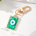 Detail of wave-edge resin keychain with green fluid texture and evil eye charm - Green