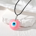 Détail macro du pendentif œil grec de style bohème avec base en résine rose et cordon noir - Rose