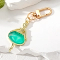 Détail du porte-clés ballerine avec monture dorée et robe en émail vert de haute qualité - Fille Cyan