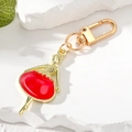 Détail d'un porte-clés ballerine dorée avec un tutu en émail rouge vif étincelant - Fille Rouge