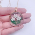 Handmade resin botanical necklace with white dried flowers and a gold metal circular frame - May Lily of the Valley (Necklace)