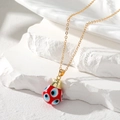 Close-up of red teardrop evil eye pendant with golden chain on white stone - Red