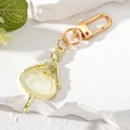 Macro detail of golden ballerina keychain with ivory resin dress on marble stones - White Girl