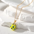 Close-up of a gold chain with a yellow teardrop Evil Eye charm on a stone base - Yellow