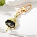 Elegant ballerina keychain in gold metal and black resin on a white marble stone surface - Black Girl