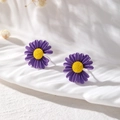 Detailansicht der violetten Gänseblümchen-Ohrringe mit gelben Staubblättern auf Weiß - Gänseblümchen-Stil / Lila