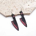 Detalle de pendientes góticos de acrílico con cuchillo ensangrentado en fondo de piedra - Cuchillo Puntiagudo