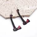 Detalle de pendientes góticos de Halloween con diseño de hacha negra con manchas de sangre - Hacha