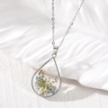 Close-up of teardrop resin pendant with real blue dried flowers and gold foil flakes - Blue Flower
