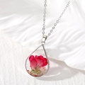 Macro shot of teardrop resin pendant featuring a real red rose flower and gold foil details - Red Flower