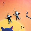 Detail shot of Halloween skeleton earrings made of acrylic on a festive orange backdrop - Skeleton Human (Cross Hook)