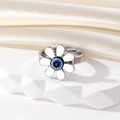 Détail d'une bague marguerite vintage argentée avec œil bleu sur tissu blanc - Fleur Argentée