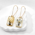 Detailed close-up of handmade resin earrings with real dried flowers and gold leaf foil - Light Blue Morning Glory