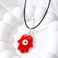 Retro red Hamsa Hand necklace with evil eye pendant on a black cord and white background - Red Glass Hamsa Hand