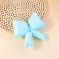 Detailed view of a light blue padded swallowtail bow charm on a woven straw mat - Blue (FJ501)